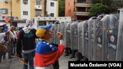 Caracas'ta polis ile konuşan bir protestocu